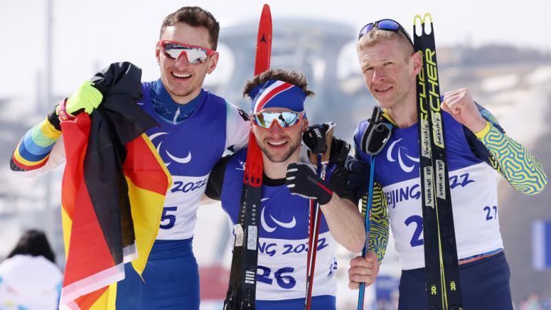 Gold medallist Benjamin Daviet of France (C), silver medallist Marco Maier of Germany (L) and bronze medallist Grygorii Vovchynskyi of Ukraine (R) celebrate their win in the Men's Sprint Free Technique Standing in the Beijing 2022 Paralympic Winter Games at Zhangjiakou National Biathlon Centre. 