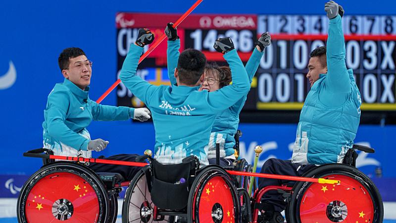 The Chinese wheelchair curling team raise their arms in the air in celebration
