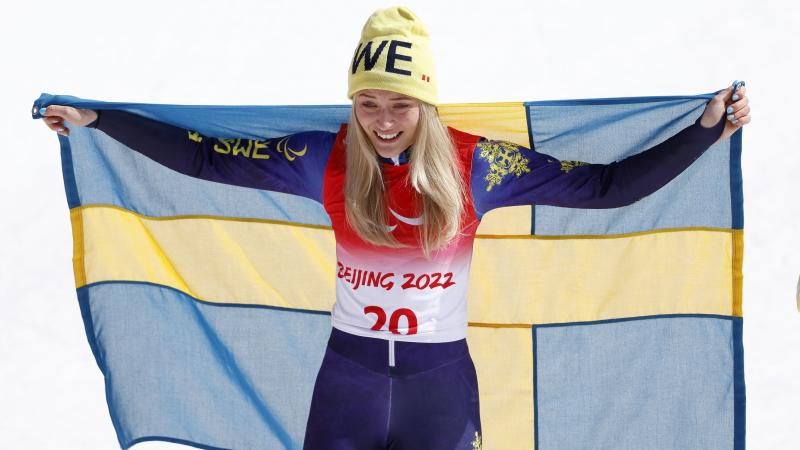 Ebba Aarsjoe celebrates with Swedish flag after winning her second gold at Beijing 2022