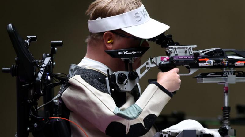 A man in a power chair competing in a shooting event with a rifle
