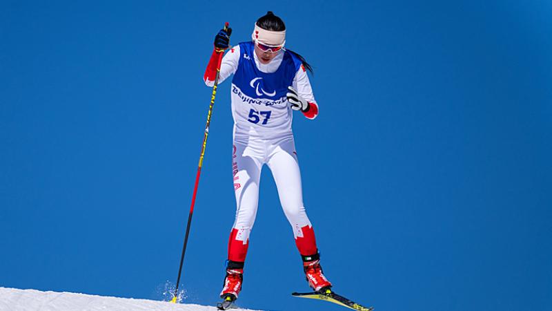 Yujie Guo of China looks determined as she skis in the women's sprint standing in front of clear blue skies