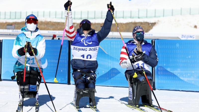 Oksana Masters of United States celebrates winning gold with silver medallist Yilin Shan of China and compatriot bronze medallist Kendall Gretsch in the women's Sprint Sitting Para Biathlon on Day One of the Beijing 2022 Paralympics Winter at Zhangjiakou National Biathlon Centre. 