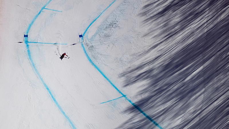 A Para Alpine sit-skier makes their way down the course during training in the shadow of the trees