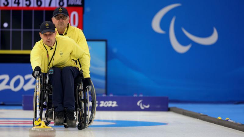 A Swedish wheelchair curler pushes the stone forward