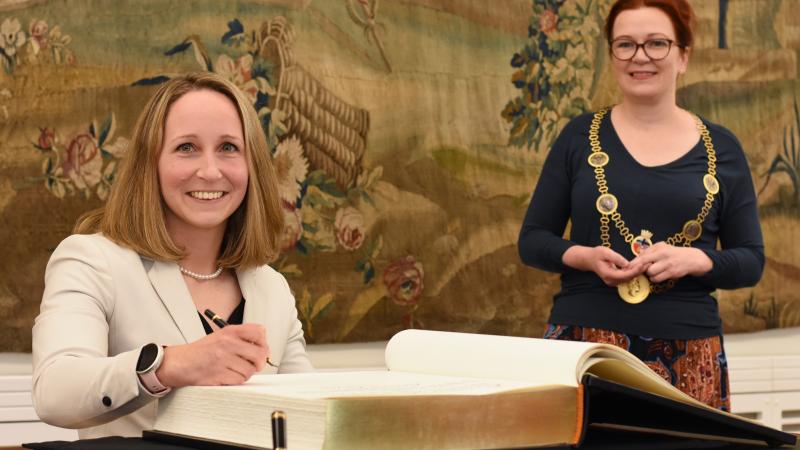 Annika Zeyen signs the Golden Book of Bonn as Bonn Mayor smiles behind