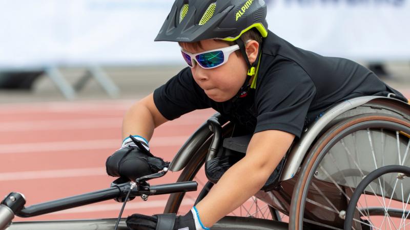 A close-up of Adrian Ruf as he pushes forward in his racing wheelchair with a look of determination on his face.