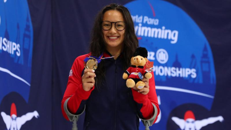 Alice Tai smiles as she holds up a bear mascot and her gold medal from the women's 100m freestyle S8 at the London 2019 World Para Swimming Championships.