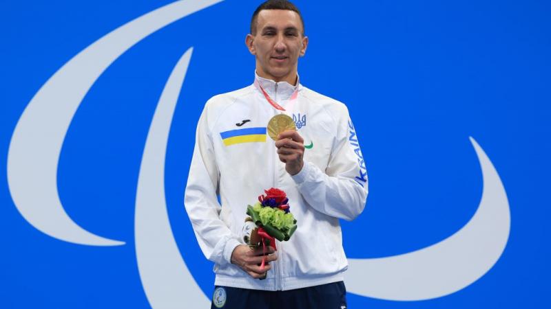 Image of a male Para swimmer in the podium with his gold medal and his flowers