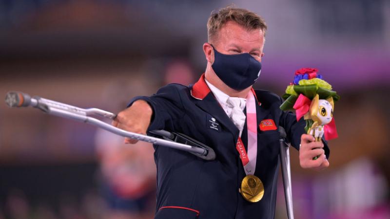 Sir Lee Pearson waves his crutch in celebration after receiving his gold medal at a victory ceremony in Tokyo.