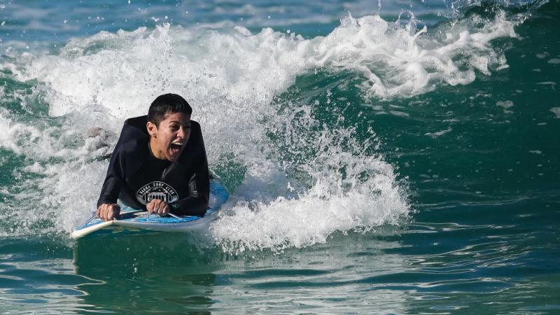 Brazil's Monique Oliveira laughs as she surfs a wave at Barra beach.