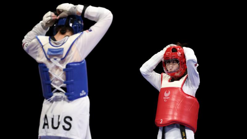 Australia's Janine Watson and Japan's Shoko Ota face each other as they adjust their helmets, preparing for their repechage match.