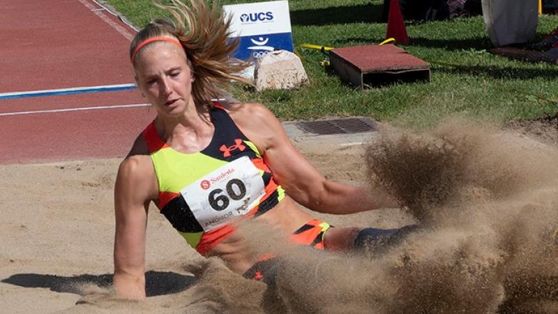 A woman landing in a sand box in a long jump competition
