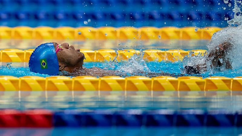 A male Para swimmer swimming backstroke in a pool