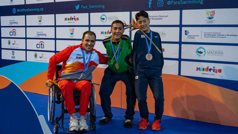 Three men with disabilities on a podium with their medals