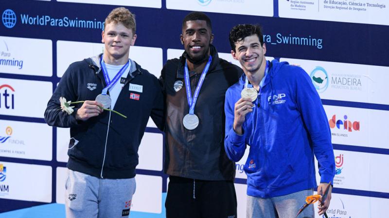 Three men standing on a podium with their medals