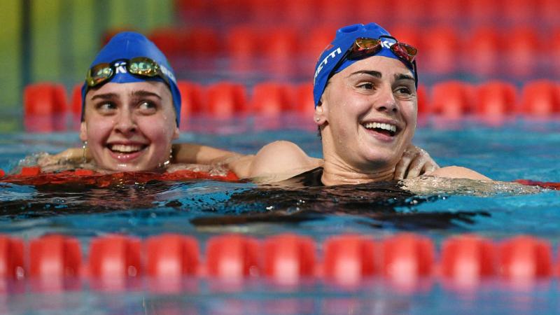 Two female swimmers with Italian caps smiling in a pool