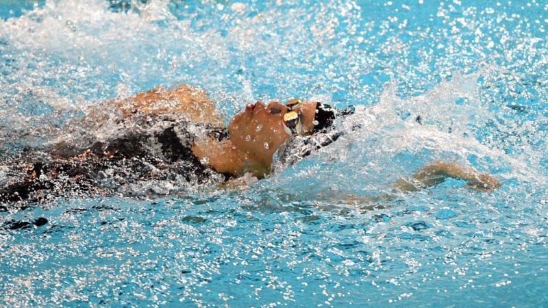 A female athlete swimming backstroke in a pool
