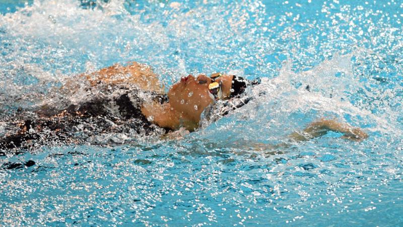 A female athlete swimming backstroke in a pool