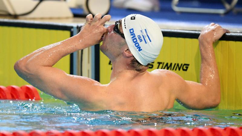 A male swimmer kissing his hand in a pool