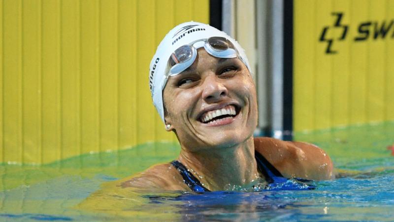 A female swimmer smiling from inside a competition pool