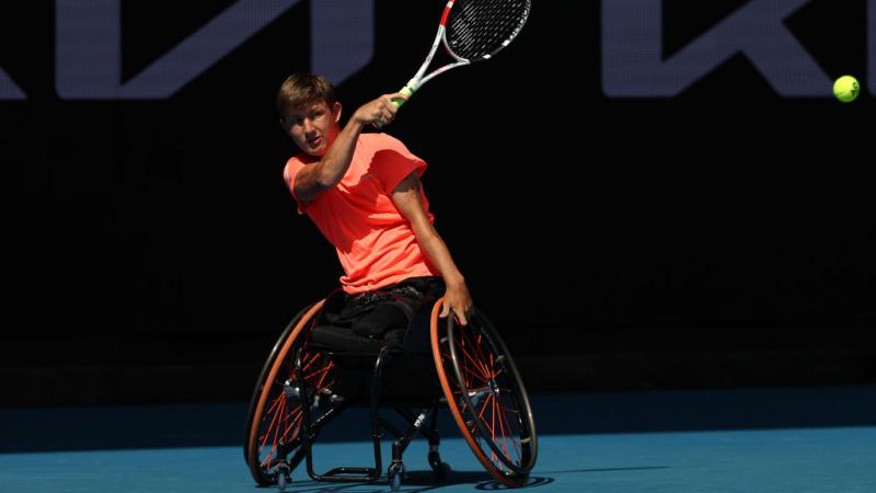 Niels Vink plays in an Australian Open match, his right hand holding his racquet and the other directing his wheelchair.