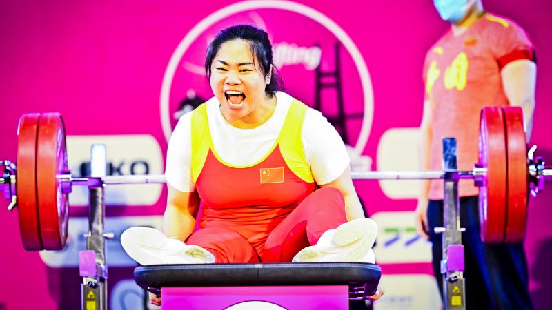 Chinese female Para powerlifter screams in celebration after a successful lift.