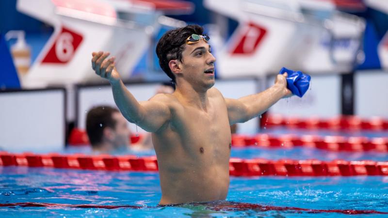 A male celebrates by stretching his hands out after a race.