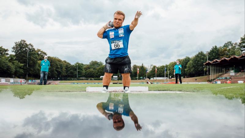 A short stature man competing in shot put