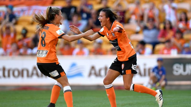 A woman who is missing her left forearm runs towards a teammate in celebration.