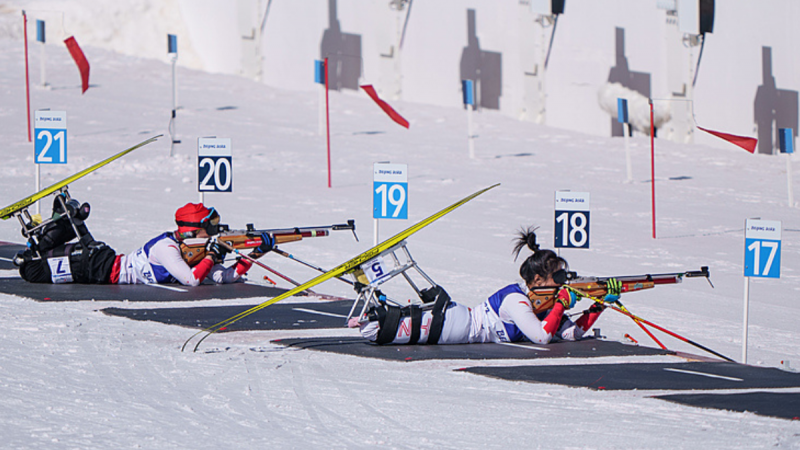 Two female athletes in a Para biathlon shooting range