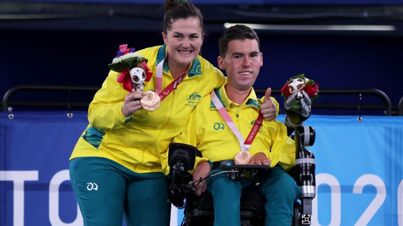 Australian boccia player Daniel Michel and ramp assistant Ashlee McClure smile on the podium after winning bronze at the Tokyo 2020 Paralympic Games.