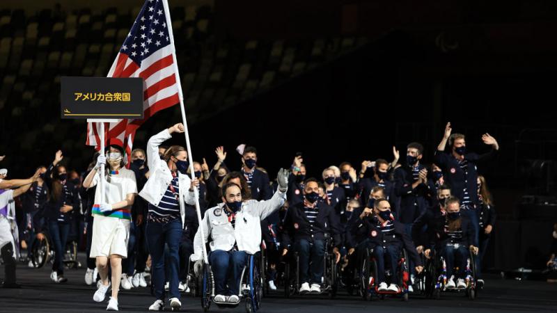 The USA delegation enters the Athletes' Parade at the Opening Ceremony of the Tokyo 2020 Paralympic Games with two flagbearers in front.