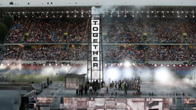 A banner reads 'Together' as post-war Birmingham is recreated onstage during the 2022 Commonwealth Games Closing Ceremony.