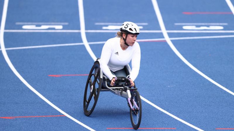 A female wheelchair racer after crossing the line in a blue track