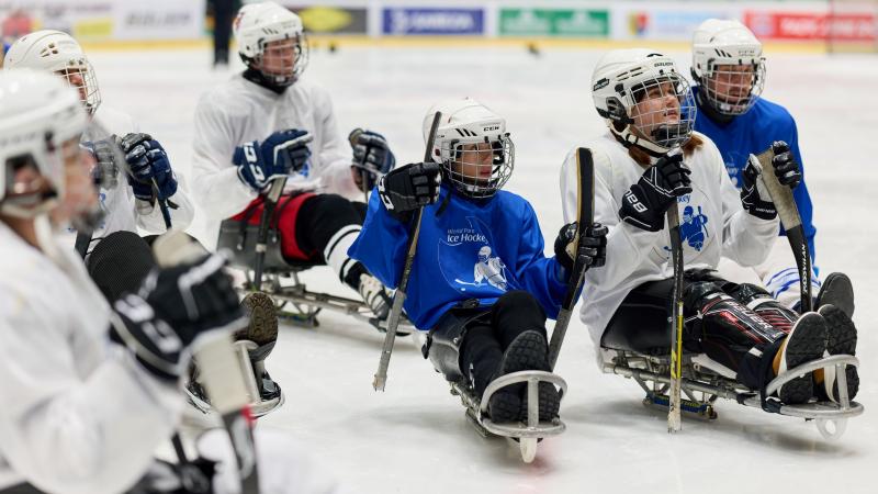 Para ice hockey players hold sticks on the ice.