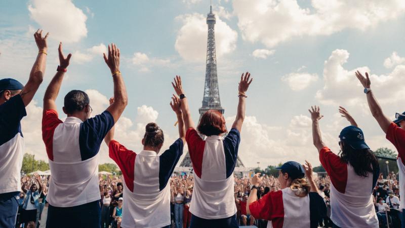 People wearing the colours of the French flag wave in front of the Eiffel tower in Paris.