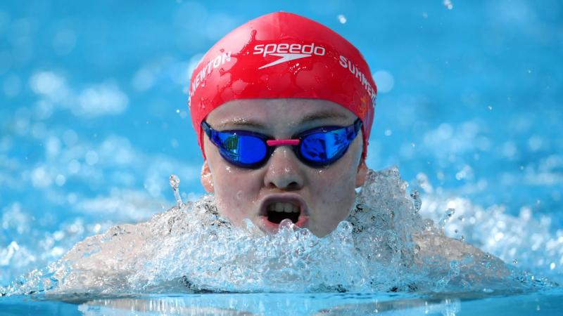 A close up of a female swimmer as she comes up for a breath during a breaststroke race.