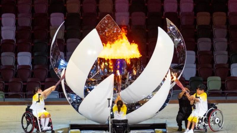 Three athletes on wheelchairs light a sphere-shaped cauldron during the Opening Ceremony of the Tokyo 2020 Paralympic Games.