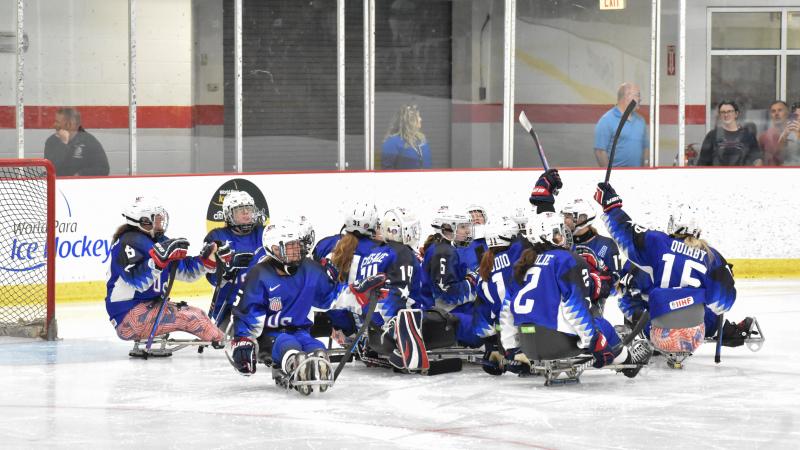 Female Para ice hockey players in blue jerseys celebrate on ice