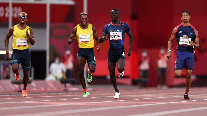 Four men running on an athletics track