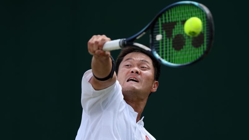 A closeup of a male tennis player as he plays a backhand during a wheelchair tennis tournament.