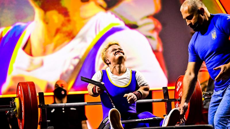 A female Para powerlifter takes off her belt and celebrates after a lift.