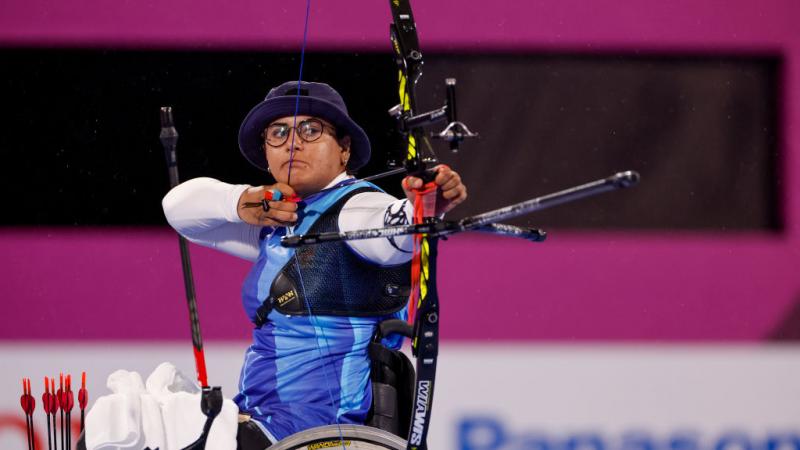 A female athlete on a wheelchair is pulling a bow at the Tokyo 2020 Paralympic Games.