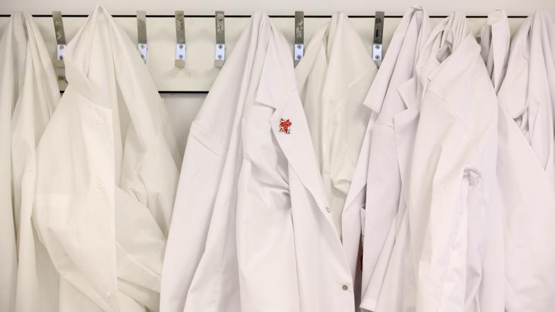 White lab coats hang on the wall in an anti-doping laboratory.