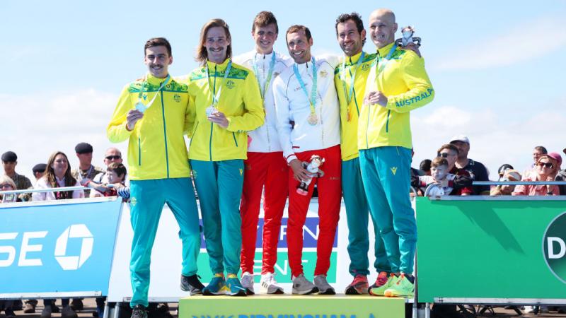 Six male athletes stand on the podium