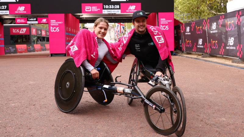 A woman and a man in racing wheelchair racers in front of the finish line of the London Marathon