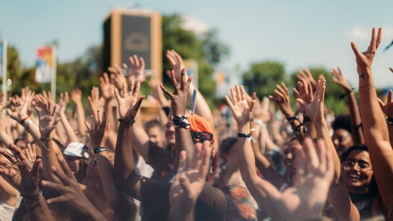 People in a large crowd raise their hands during the Paris 2024 handover celebration.