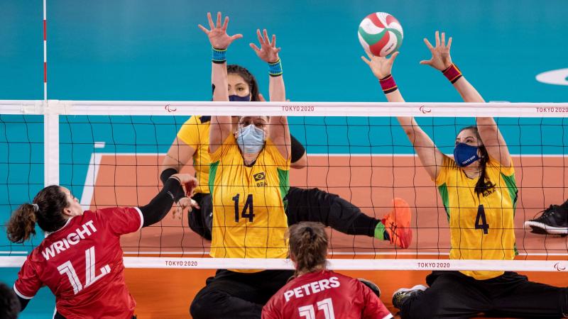 A female sitting volleyball player from Brazil plays the ball during a match against Canada.