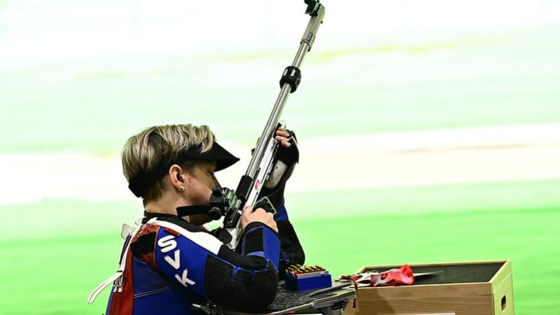 A woman with a rifle in a shooting range during a shooting Para sport competition