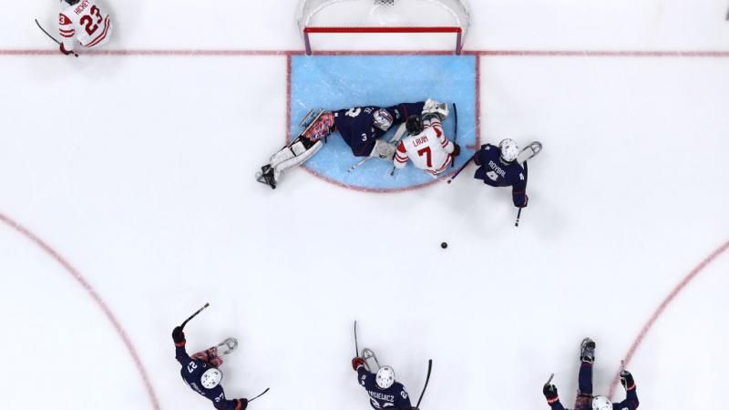 An aerial view of a Para ice hockey game with five players on ice